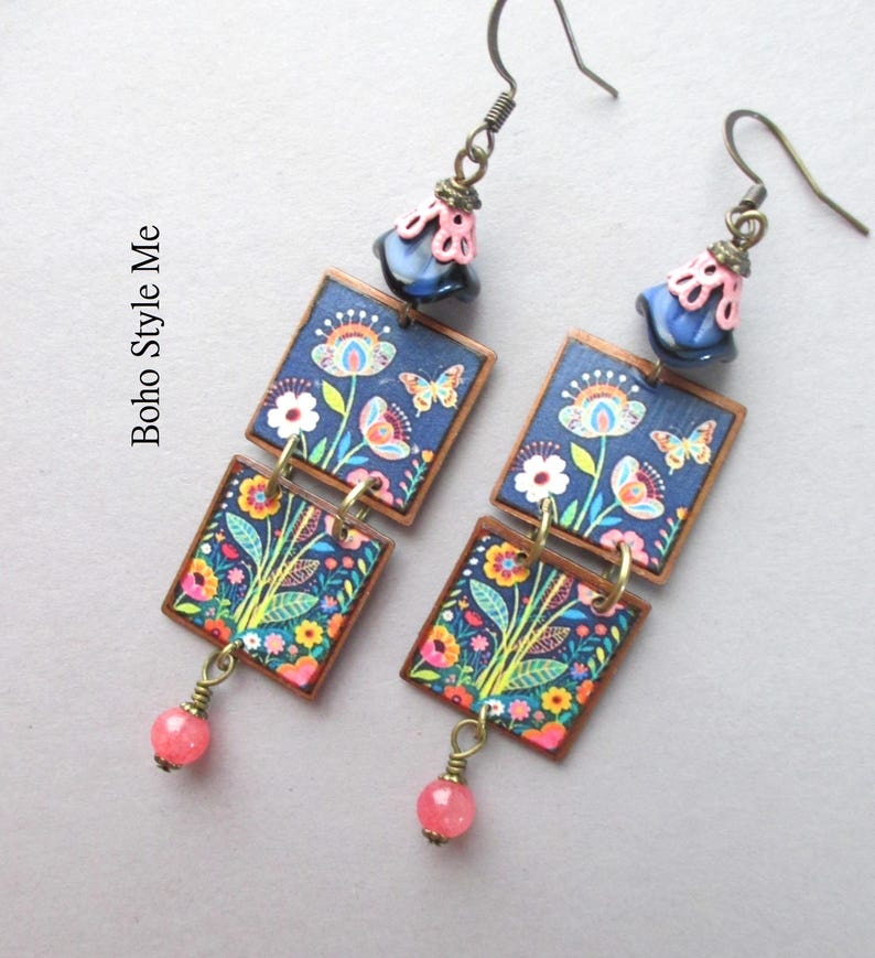 Puede incluir: Un par de pendientes colgantes con dos colgantes cuadrados con estampado floral y de mariposas en azul oscuro, acentuados por una cuenta rosa y azul en la parte superior y una peque&ntilde;a cuenta rosa en la parte inferior, con el texto Boho Style Me.