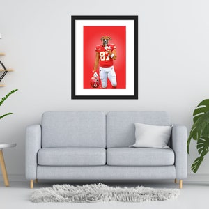 May include: Framed art print showing a boxer dog in a football uniform, number 87. The dog is wearing a red jersey and white trousers, holding a helmet. The background is a solid red. The print is in a black frame.