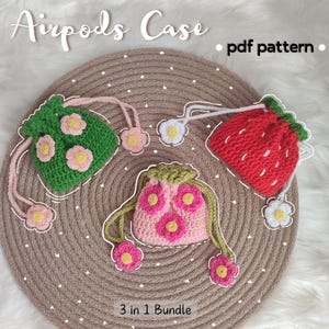 Könnte beinhalten: Drei gehäkelte Airpods-Hüllen im Bundle. Die Hüllen sind in Form einer Erdbeere, einer Blume und eines grünen Blattes. Die Hüllen sind alle mit rosa und gelben Blumen verziert. Der Text "3 in 1 Bundle" ist auf dem Bild sichtbar. Der Text "pdf pattern" ist ebenfalls auf dem Bild sichtbar.