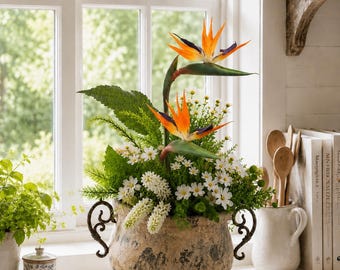 Ett blomsterarrangemang med strelitzior som kan användas året runt ser väldigt realistiskt ut i en högkvalitativ antik keramikkruka. Bordsdekoration.