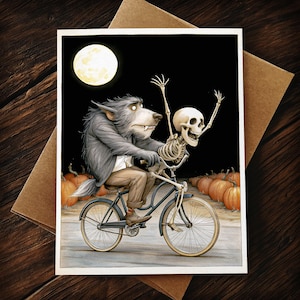 May include: A rectangular greeting card featuring an illustration of a grey werewolf wearing brown trousers riding a blue bicycle with a human skeleton sitting on the handlebars. A full moon shines in the black sky above orange pumpkins.