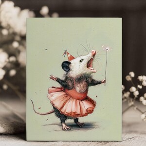 K&ouml;nnte beinhalten: Eine skurrile Illustration eines Opossums mit Partyhut und rosa Tutu, das einen Wunderkerzenstab h&auml;lt. Das Opossum hat den Mund offen, als w&uuml;rde es singen oder schreien, vor einem hellgr&uuml;nen Hintergrund.