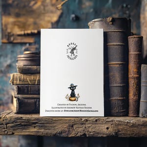 Pu&ograve; includere: Un biglietto di auguri bianco con un gatto nero con un cappello su una zucca. Il biglietto ha il testo "RUGGED JACKALOPE" e "CREATED IN TUCSON, ARIZONA". Il biglietto &egrave; su una mensola di legno con vecchi libri.