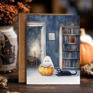 Pu&ograve; includere: Biglietto di auguri a tema Halloween con un'illustrazione ad acquerello. Un fantasma legge un libro seduto su una zucca, con un gatto nero nelle vicinanze. Lo sfondo mostra una stanza con una libreria e una lampada accesa.