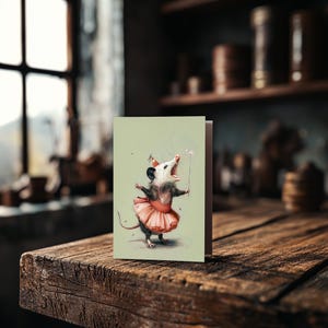 K&ouml;nnte beinhalten: Eine Gru&szlig;karte mit einer Illustration eines Opossums mit Partyhut und rosa Tutu, das einen Zauberstab h&auml;lt. Das Opossum ist mit offenem Mund dargestellt. Die Karte hat einen hellgr&uuml;nen Hintergrund.
