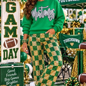 Puede incluir: Una sudadera verde brillante de cuello redondo con la palabra Mustangs en letras plateadas, combinada con pantalones de talle alto con un patrón de cuadros de lentejuelas verdes y doradas y zapatillas blancas con una estrella verde.