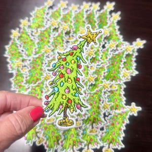 May include: A pile of green Christmas tree patches with colorful ornaments and a yellow star on top. The patches are embroidered and have a white background.