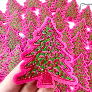 Puede incluir: Colección de parches de árbol de Navidad rosas con detalles bordados en verde. Los parches tienen una textura suave, similar al fieltro, y están diseñados con un estilo festivo. Ideales para manualidades temáticas navideñas.