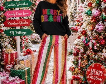 Peut inclure: Un sweat-shirt noir à manches longues avec le texte MERRY AND BRIGHT en lettres pailletées rouges, vertes et dorées, associé à un pantalon large à rayures verticales en sequins rouges, verts, dorés et argentés.