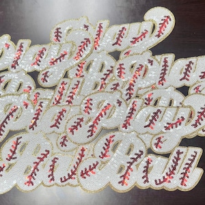 以下が含まれることがあります： 「Play Ball」と綴られた、白、金、赤のビーズでできたパッチのセット。パッチは野球ボールの形をしており、赤いステッチが施されています。