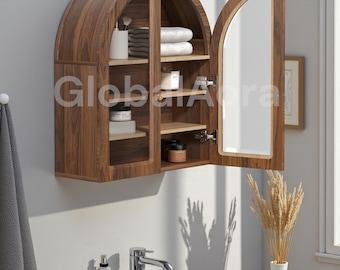 Könnte beinhalten: Ein hölzerner, bogenförmiger Badezimmerschrank mit Spiegeltür. Der Schrank hat mehrere Regale mit Handtüchern, Toilettenartikeln und anderen Badezimmerutensilien. Der Schrank ist an einer hellgrauen Wand montiert, darunter sind ein Waschbecken und eine Armatur zu sehen.