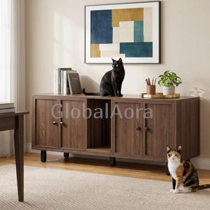 May include: A dark brown wooden sideboard featuring four cabinet doors and a central open shelf. A black cat sits on top of the sideboard next to a row of books and a potted plant. A calico cat sits on the floor in front of the furniture piece.