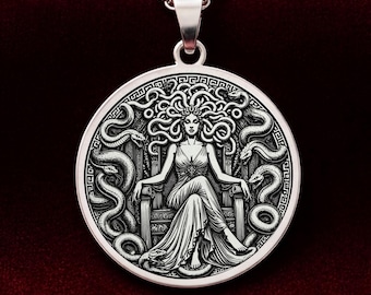 May include: A silver-colored pendant necklace featuring a detailed depiction of Medusa. The round pendant showcases Medusa seated, surrounded by snakes, with a matching silver chain. The design is intricate, with a focus on the mythological figure.