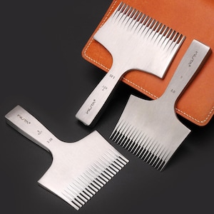 May include: Three stainless steel leathercraft tools with toothed edges, labeled with measurements. The tools are arranged on a dark surface with a brown leather item in the background. The tools have the brand name "WUTA" printed on them.