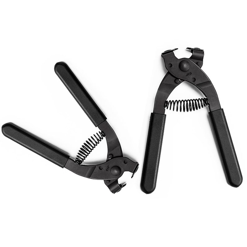 May include: Two black metal pliers with black handles and a spring mechanism. The pliers are designed for a specific task, with a curved head and a small opening at the tip. The tools are set against a white background.