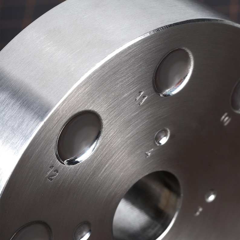 May include: A silver metal disc with six evenly spaced holes around the edge. The holes are numbered 11, 12, 1, 2, 3, and 4.
