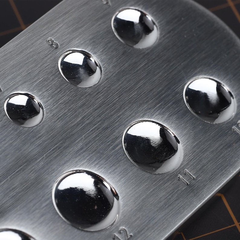 May include: A metal gauge with 12 round, polished metal discs of varying sizes. The gauge is marked with numbers 8 through 12.