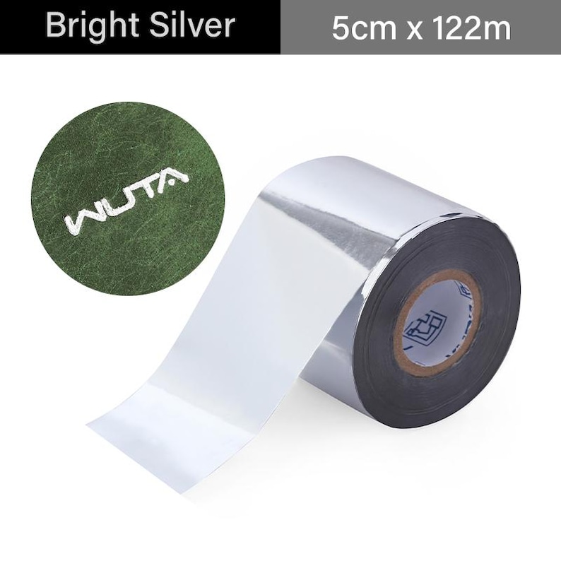 May include: Bright silver roll of material, 5cm x 122m, with a shiny, reflective surface. The roll is partially unrolled, revealing the inner core. A green circular patch with the word "WUTA" in white is in the upper left.
