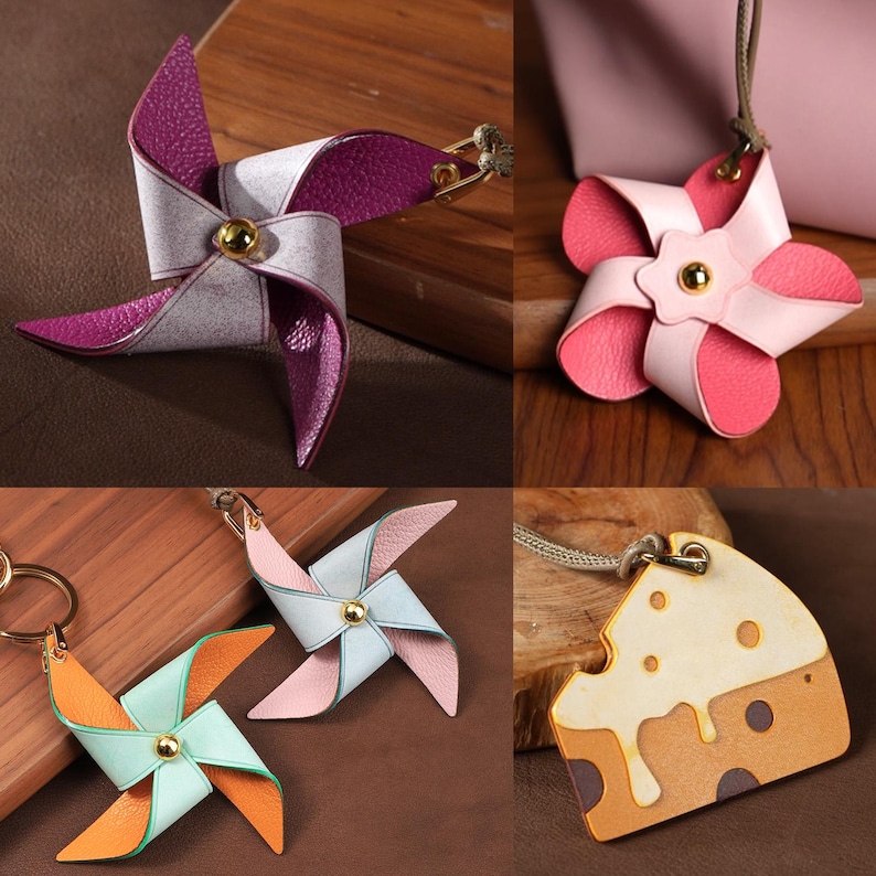 May include: A selection of leather pinwheel keyrings and charms in various colours. The pinwheels have combinations of pink, purple, orange, and blue, with gold-coloured hardware. One charm is shaped like a slice of cheese.