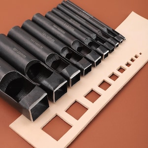 May include: Set of 10 metal leather hole punches in various sizes, ranging from 6x6mm to 20x20mm. The punches are arranged in order of size, with the smallest on the left and the largest on the right. The punches are on a piece of beige leather with cutouts that match the size of each punch.