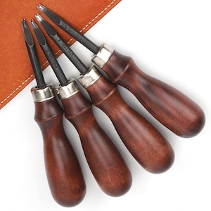 May include: Set of four leather crafting tools with wooden handles. The tools have metal blades with the words "WULKA 2" and "WULKA 3" engraved on them.