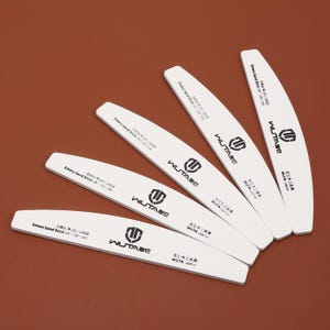 Puede incluir: Cinco limas de uñas blancas con texto negro y un logotipo negro. El texto dice "Emery Sand Stick" y "WUTA". Las limas son curvadas y tienen diferentes niveles de grano: 100/240, 200/240, GA100/240, 100/2400 y 200/2400.