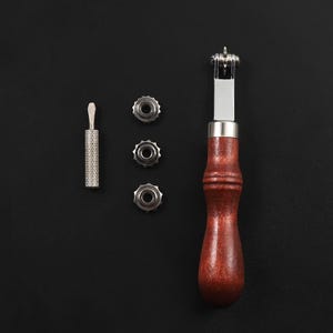 May include: A leather stitching tool with a wooden handle and three interchangeable stitching wheels. The tool is used for stitching leather together.