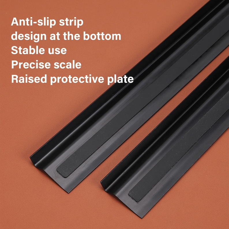 May include: Two black metal rulers with anti-slip strips on the bottom. The rulers have raised edges for protection. The text on the image reads: "Anti-slip strip design at the bottom Stable use Precise scale Raised protective plate"
