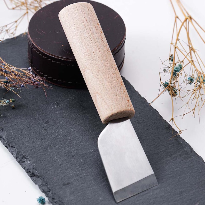 May include: A wooden handled knife with a stainless steel blade. The knife is resting on a black slate surface.