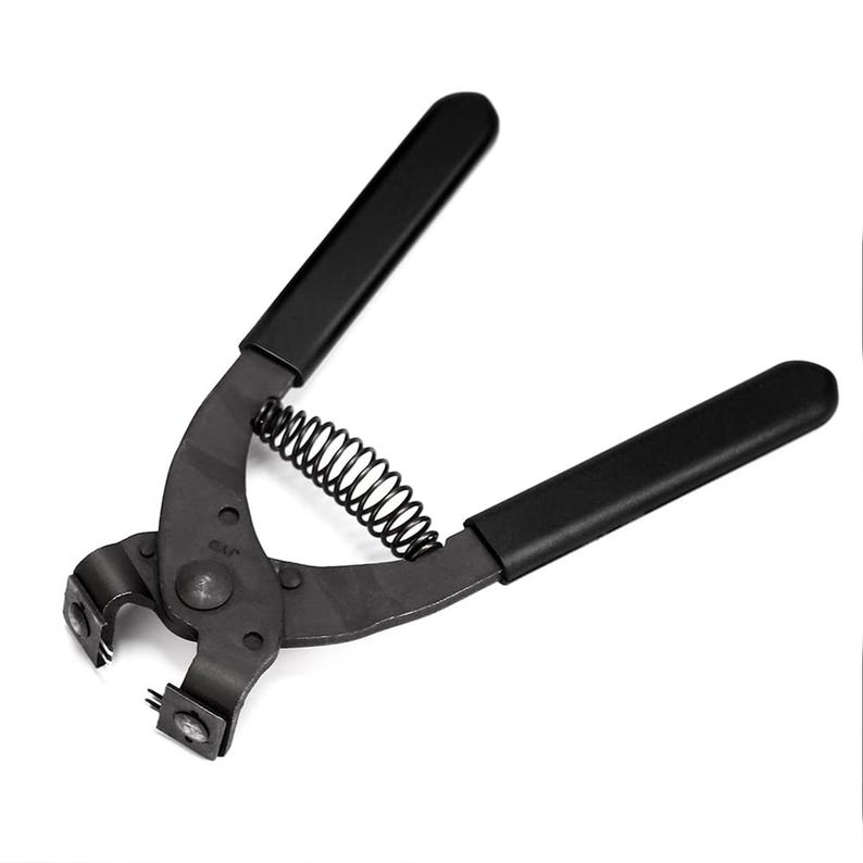 May include: A black metal tool with a spring and two black handles. The tool has a curved design with a small, square opening at the end. The tool is designed for a specific purpose, likely related to crafting or repair.