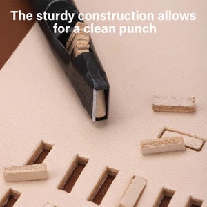 May include: Close-up of a leather punch tool with a rectangular cutting edge. The tool is black and is shown in use, creating rectangular holes in a light tan leather surface. The text "The sturdy construction allows for a clean punch" is visible.