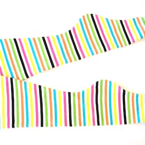 May include: Two colorful striped leg warmers. The leg warmers feature vertical stripes in a variety of colors, including pink, yellow, green, orange, black, and blue. The background is white.