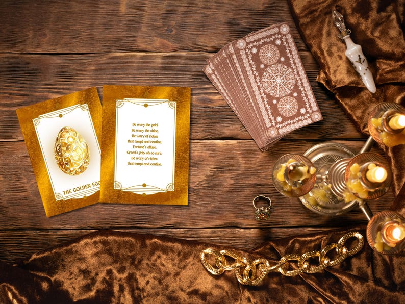 Pode incluir: Uma composi&ccedil;&atilde;o de natureza morta com um baralho de cartas de tar&ocirc;, dois cart&otilde;es dourados com texto e uma ilustra&ccedil;&atilde;o de ovo dourado, uma corrente de ouro, um anel e velas acesas. O texto nos cart&otilde;es diz "Be wary the gold..." e "The Golden Egg."