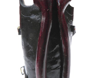 May include: A black leather arm guard with a red leather design. The arm guard has a strap and buckle closure.