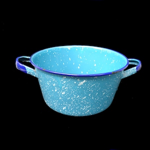 May include: A speckled turquoise enamelware pot with two handles. The pot has a dark blue rim and handles. White speckles are scattered across the turquoise surface. The pot is set against a black background.