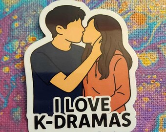 May include: A sticker featuring a couple kissing, with the text "I LOVE K-DRAMAS" in white block letters. The man is wearing a navy blue shirt, and the woman is wearing an orange hoodie. The sticker has a white border and is on a colorful background.