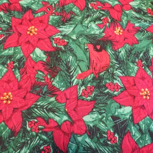 May include: A festive fabric featuring a repeating pattern of red poinsettias, green pine needles, and red berries. A red cardinal bird is also featured in the design. The fabric is suitable for Christmas-themed crafts and decorations.