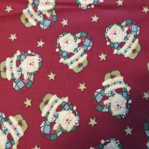 May include: Red fabric with a repeating pattern of patchwork Santa Claus figures. Each Santa is wearing a red hat, white beard, and a patchwork coat with green, blue, and yellow accents. The background is a solid red with small gold stars.