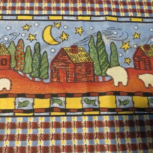 May include: Fabric with a whimsical, folk art design. Features red cabins, trees, sheep, a crescent moon, and stars against a blue sky. The border has fish and a plaid pattern in red, blue, and yellow.