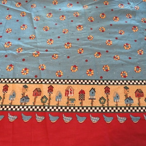May include: Blue fabric with a repeating pattern of yellow flowers and red dots. The bottom border features a black and white checkered pattern with a row of colorful birdhouses and a row of blue birds on a red background.