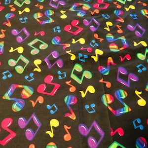 May include: Black fabric with a repeating pattern of colorful musical notes. The notes are in various shades of red, orange, yellow, green, blue, purple, and pink. Some notes have a rainbow stripe pattern.