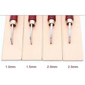 May include: Four leathercraft tools with wooden handles and metal blades, each on a separate beige leather base. The blades are labeled with sizes: 1.0mm, 1.5mm, 2.0mm, and 2.5mm. The tools are for leather working.