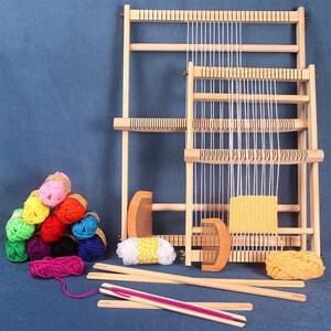 May include: A wooden loom with a yellow woven piece on it. The loom has a wooden frame with a white string warp. There are colorful balls of yarn and a wooden comb in the image.