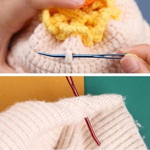 May include: A blue metal yarn needle threaded with yellow yarn passing through a cream-colored crocheted fabric, and a red metal yarn needle inserted into a beige knitted fabric, demonstrating the use of large-eyed needles for yarn work.