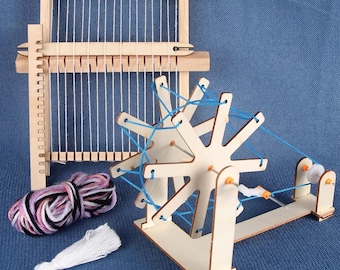 May include: A wooden weaving loom with white warp threads, a separate wooden shuttle, a wooden yarn winder with blue yarn, a ball of variegated pink, black, and white yarn, and a small bundle of white yarn, all crafted from light-colored wood.