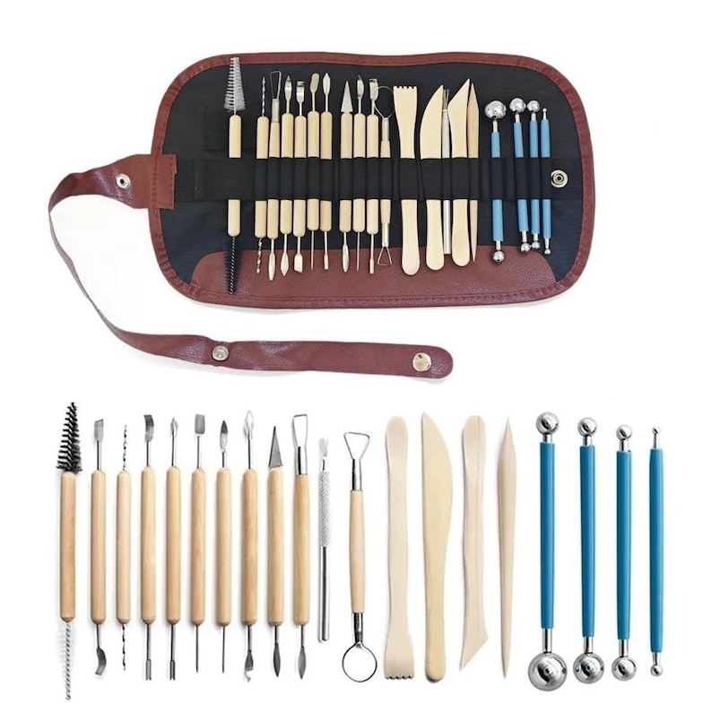 May include: A set of pottery tools, including various sculpting and shaping implements. The tools have wooden handles and metal tips, with some tools featuring blue handles. The set is displayed in a brown leather-like roll-up case.