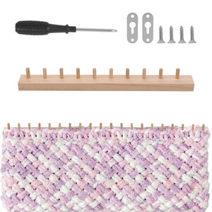 May include: A wooden knitting loom with eleven pegs, featuring a partially completed project in a variegated pink, purple, and white yarn. The set includes a black-handled screwdriver, two metal wall-mounting brackets, and four silver screws.