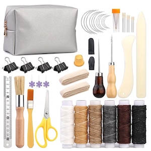 Puede incluir: Un kit de artesanía en cuero con una bolsa plateada, agujas, carretes de hilo y varias herramientas. Incluye tijeras, pinceles, una regla y clips de encuadernación. El kit presenta una variedad de colores y materiales, perfecto para proyectos de marroquinería.
