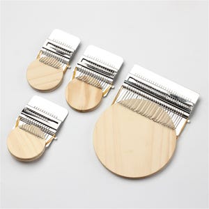 May include: Three circular wooden embroidery hoops with metal frames. The hoops are different sizes and are arranged in a row from largest to smallest.