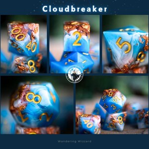 May include: A set of blue and white dice with gold accents and swirling patterns. The dice are numbered 1 through 6. The dice are labeled "Cloudbreaker".